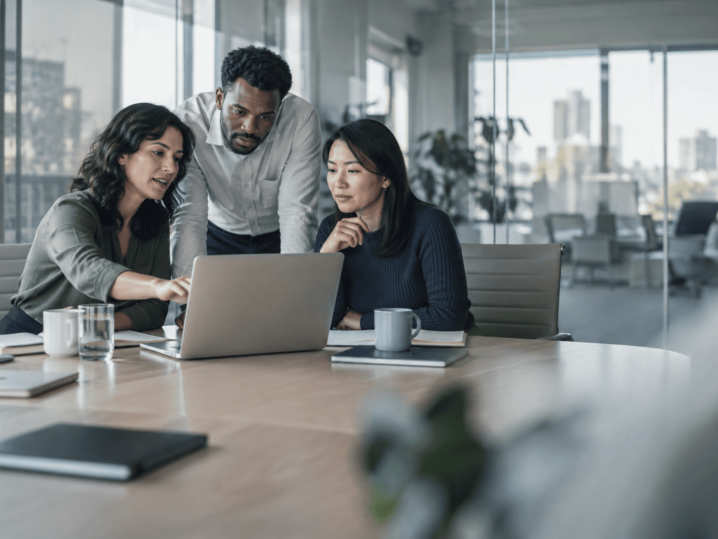 An HR team reviewing hiring status together at a laptop