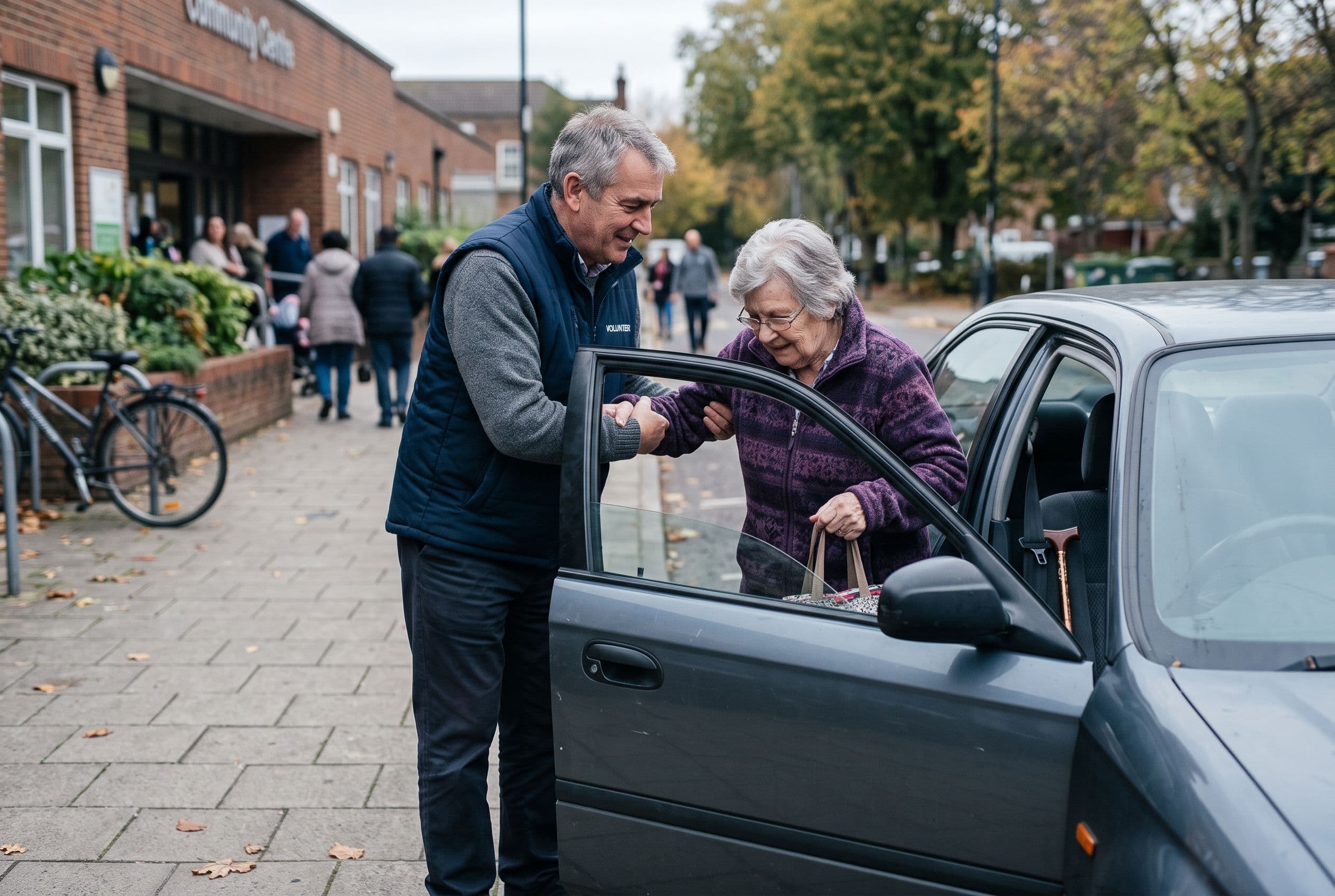 A volunteer driver helping an older adult into a car